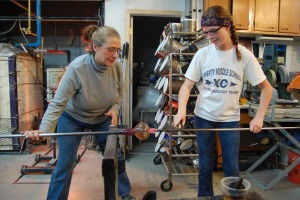Annette Baron (left) and Raquel Goosey (right) use a punty to transfer a piece.