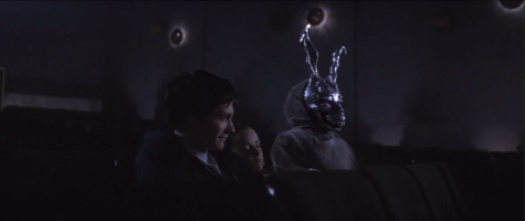 Jake Gyllenhaal, Jena Malone, and a mysterious figure sit in an empty movie theater in "Donnie Darko".